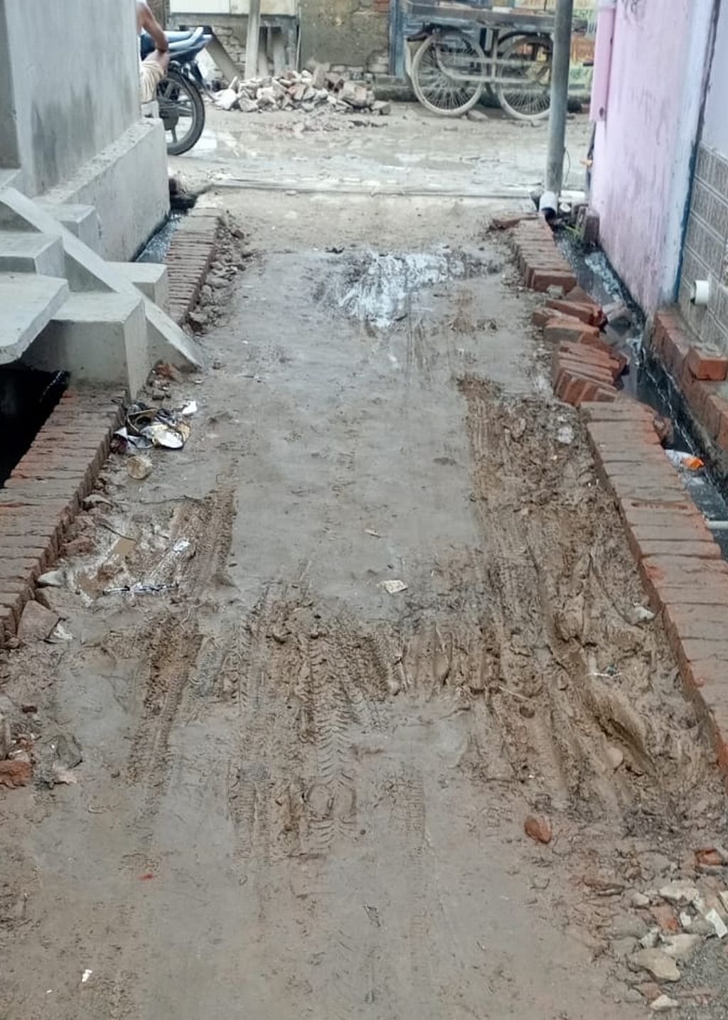 गली में ईंटे लगाकर छोड़ गया ठेकेदार, कीचड़ मे फिसलकर गिर रहे लोग